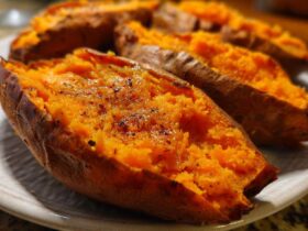 Close-up of fluffy, bright orange baked sweet potatoes split open and seasoned with pepper.