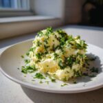 A mound of homemade garlic butter, richly topped with chopped fresh parsley, sitting on a white plate.