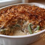 Close-up of a creamy green bean casserole topped generously with crispy fried onions.