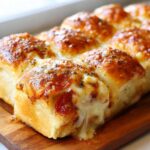 Close-up of gooey, cheesy pizza sliders with melted mozzarella and pepperoni, sprinkled with herbs.