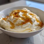 A white bowl filled with fluffy ricotta dip topped generously with golden honey.