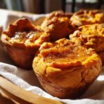 Close-up of individual baked sweet potatoes mashed and formed into muffin shapes, topped with a shiny glaze and cinnamon.