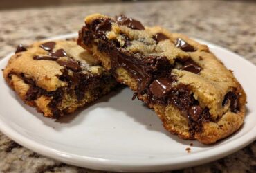 Close-up of a thick chocolate chip cookie broken in half, revealing a gooey, melted chocolate center.
