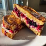 Two halves of golden brown stuffed french toast filled with creamy cheese and mixed berries.