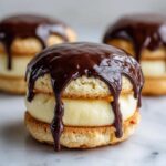 A close-up of one decadent boston cream pie cookies filled with cream and topped with dripping dark chocolate ganache.