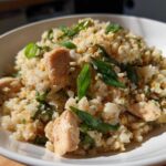 Close-up of a white bowl filled with chicken cauliflower fried rice topped with fresh green onions.