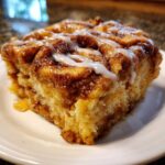 Close-up of a moist slice of cinnamon roll apple pie topped with a sweet white icing drizzle.