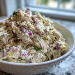 A generous serving of high-protein cottage cheese chicken salad mixed with red onion and dill in a white bowl.