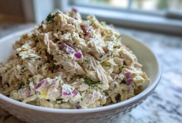 A generous serving of high-protein cottage cheese chicken salad mixed with red onion and dill in a white bowl.