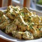 Close-up of bite-sized pieces of creamy coconut lime chicken coated in a rich sauce and garnished with fresh parsley.
