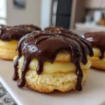 Close-up of one of the decadent boston cream pie cookies, featuring vanilla filling and dripping dark chocolate ganache.