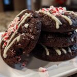 A stack of rich, fudgy double chocolate peppermint cookies drizzled with white chocolate and topped with crushed candy canes.