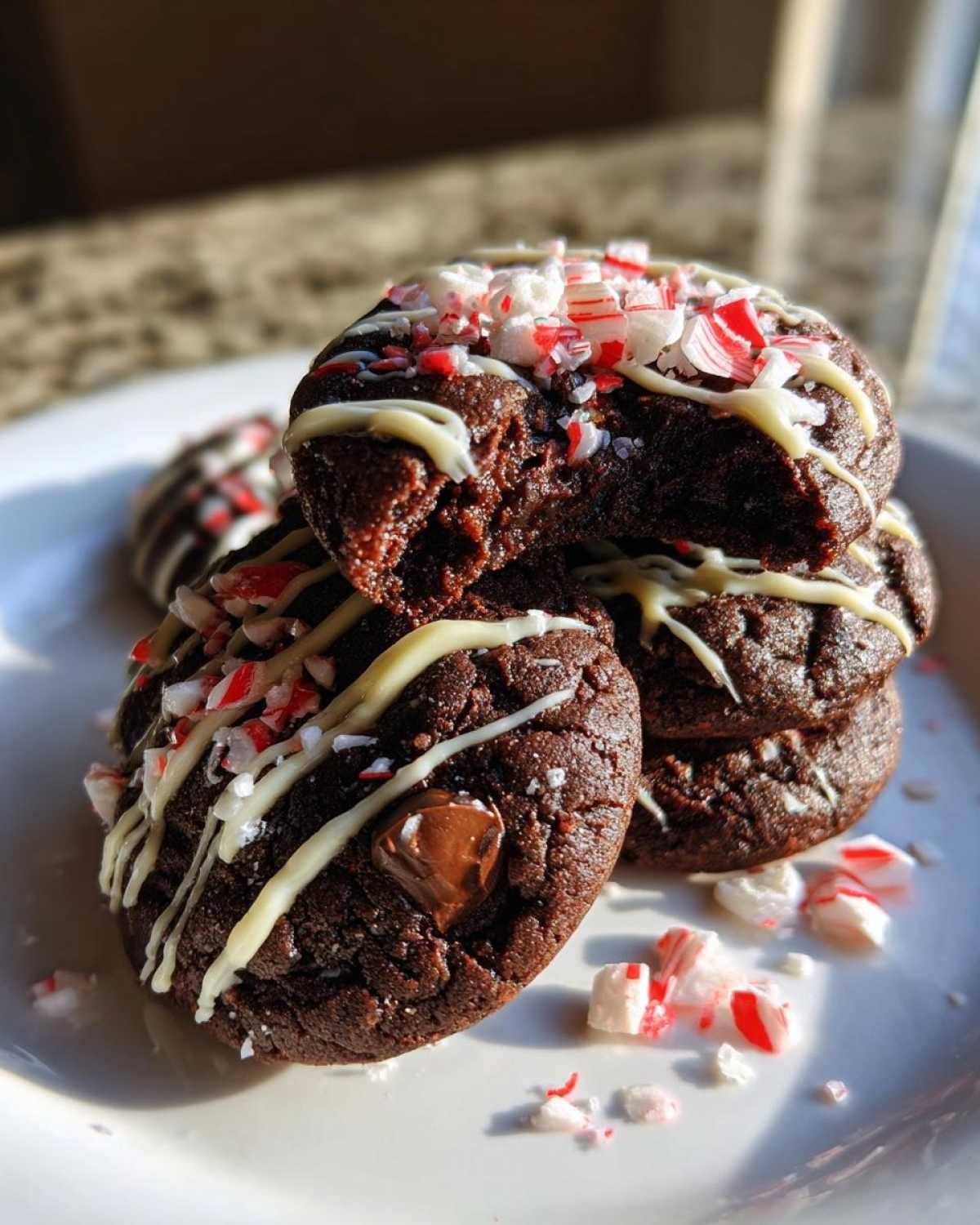 Stack of fudgy double chocolate peppermint cookies drizzled with white chocolate and topped with crushed candy canes.