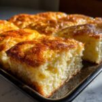 Close-up of a square cut piece of fluffy sheet pan pancakes with a golden, slightly caramelized top.