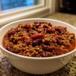 Close-up of a white bowl filled with rich, hearty high protein chili featuring ground meat and dark red kidney beans.