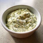 Creamy homemade tartar sauce recipe, flecked with green herbs and lemon zest, served in a white bowl.