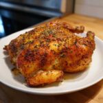 A perfectly roasted, golden brown spatchcock chicken seasoned with herbs, resting on a white platter.