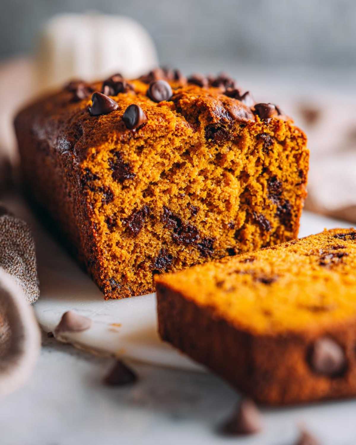 Close-up of a moist chocolate chip pumpkin bread loaf, with one slice cut off.