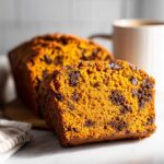 Close-up of a moist slice of chocolate chip pumpkin bread showing its rich orange color and texture.