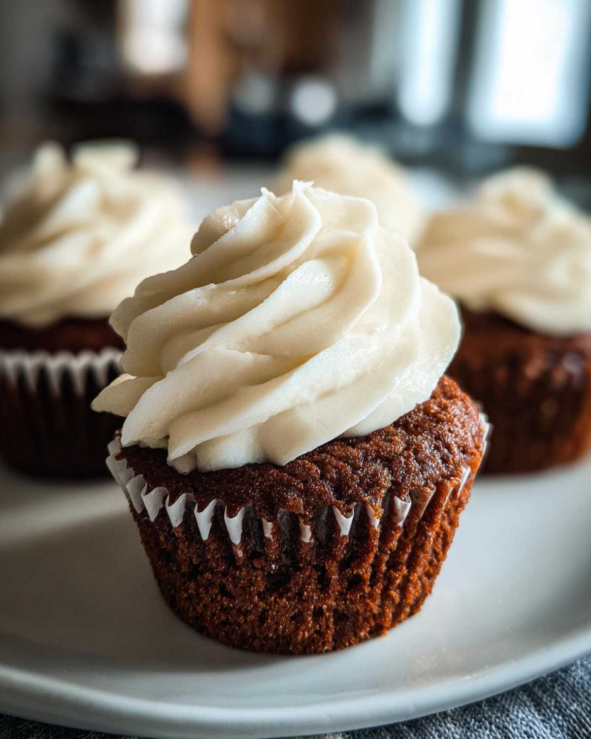 Close-up of one moist gingerbread cupcakes topped with a swirl of white cream cheese frosting.