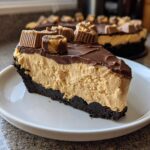 A decadent slice of no-bake peanut butter pie featuring a thick peanut butter filling, chocolate topping, and mini peanut butter cups.