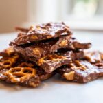 A stack of broken pieces of peanut butter pretzel bark, featuring chocolate, pretzels, and sea salt.