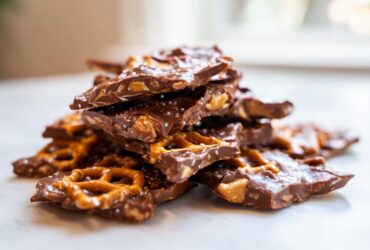 A stack of broken pieces of peanut butter pretzel bark, featuring chocolate, pretzels, and sea salt.