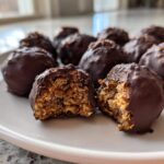 Close-up of chocolate-covered pecan pie balls, one cut in half revealing the textured, nutty interior.