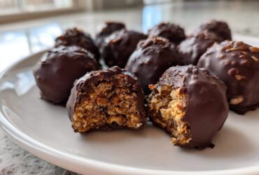 Close-up of chocolate-covered pecan pie balls, one cut in half revealing the textured, nutty interior.