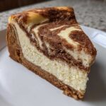 A close-up of a single slice of creamy snickerdoodle cheesecake featuring a beautiful cinnamon-sugar swirl.