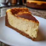 A perfect slice of creamy eggnog cheesecake recipe with a thick graham cracker crust and cinnamon topping.