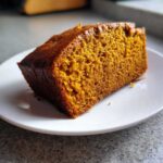 Close-up of a thick slice of moist pumpkin bread showing its rich orange color and texture.