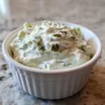 A close-up of creamy, chunky homemade tartar sauce recipe served in a small white fluted ramekin.