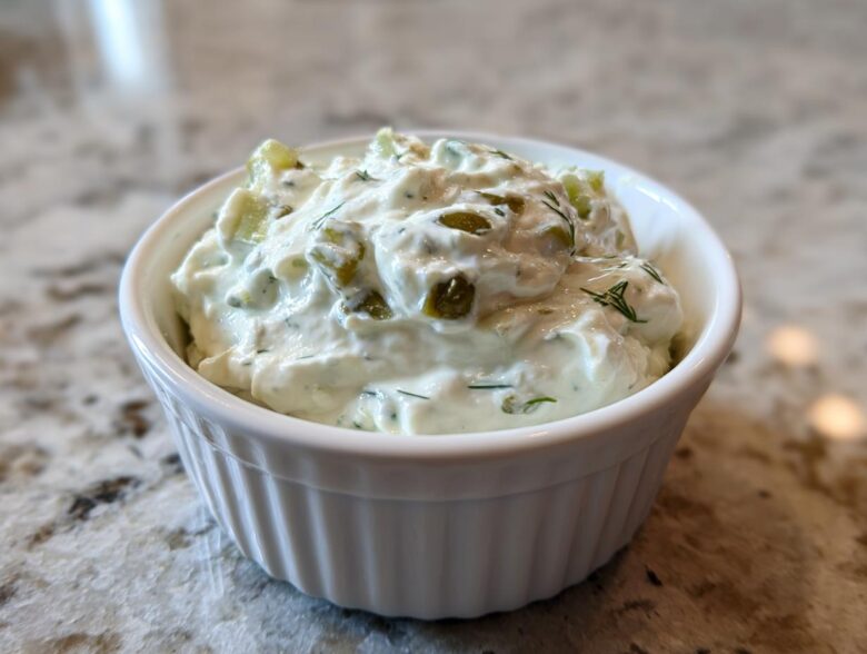 A close-up of creamy, chunky homemade tartar sauce recipe served in a small white fluted ramekin.