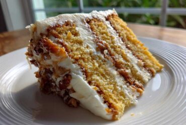A close-up slice of white German chocolate cake showing layers of yellow cake, white frosting, and pecan/coconut filling.