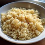 A close-up of fluffy, lightly browned cauliflower rice served in a white bowl, ready to eat.