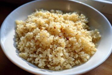 A close-up of fluffy, lightly browned cauliflower rice served in a white bowl, ready to eat.