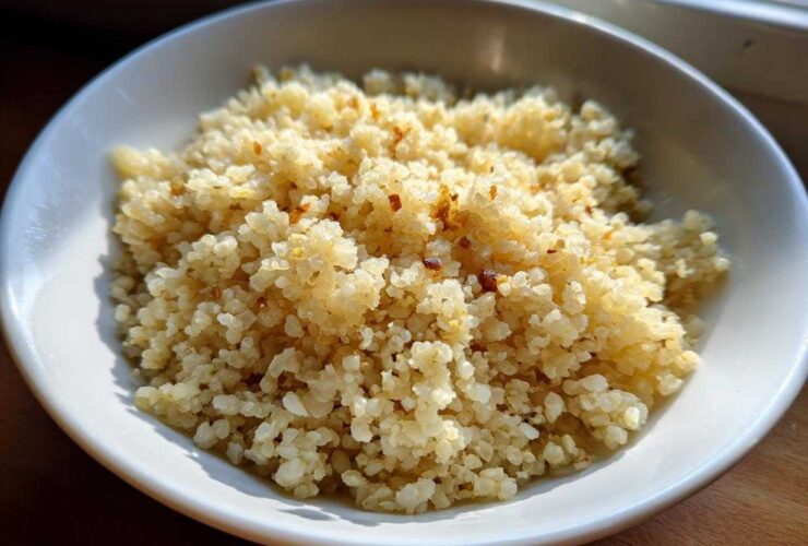 A close-up of fluffy, lightly browned cauliflower rice served in a white bowl, ready to eat.