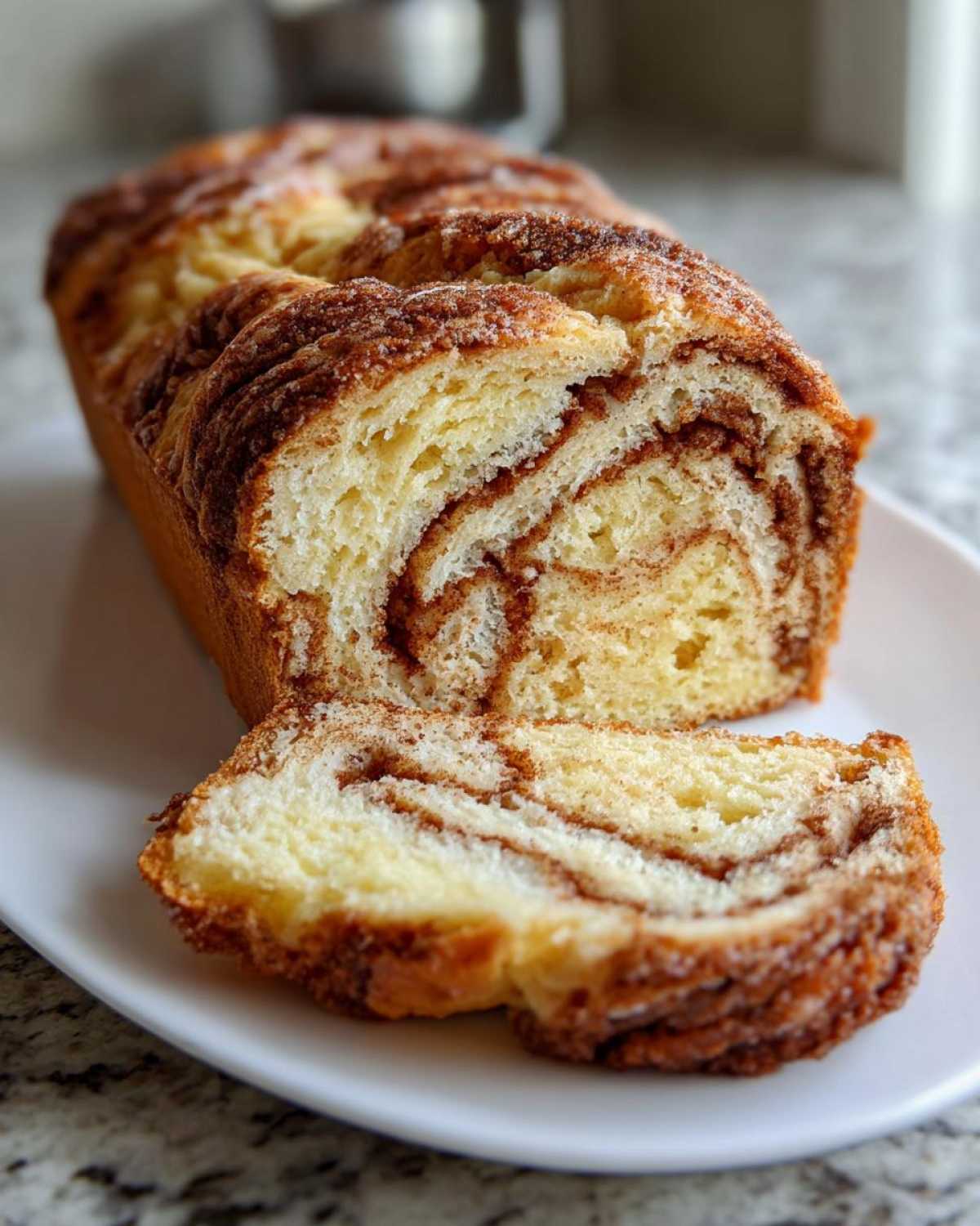 A close-up of a freshly baked loaf of cinnamon bread, sliced to show the beautiful swirl pattern inside.
