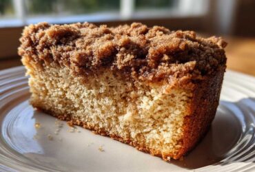 Close-up of a moist slice of coffee cake featuring a thick, dark brown cinnamon streusel topping.