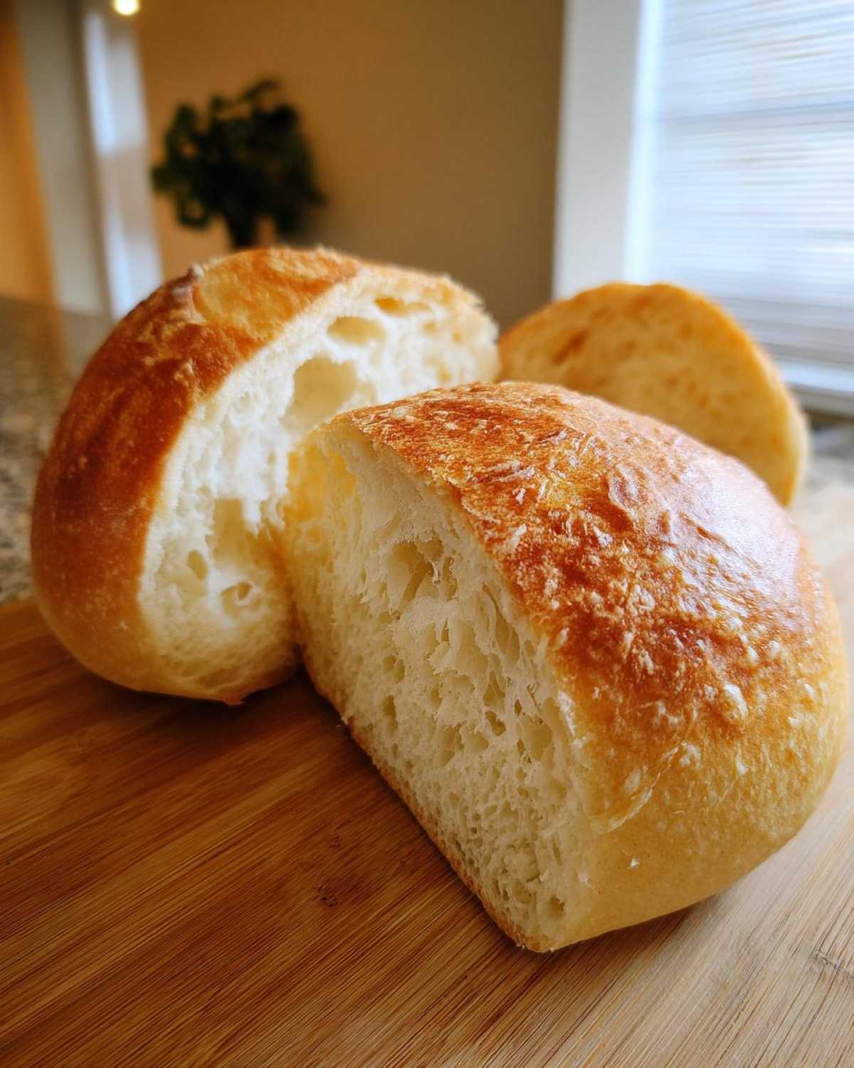 Close-up of a freshly baked bread bowl cut in half, showing the soft, airy interior crumb.