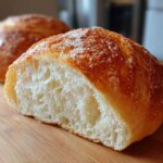 Close-up of a freshly baked roll, cut in half to show the soft, airy interior, perfect for bread bowls.