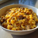 Close-up of a bowl filled with creamy, cheesy cheeseburger casserole featuring macaroni pasta and ground beef.