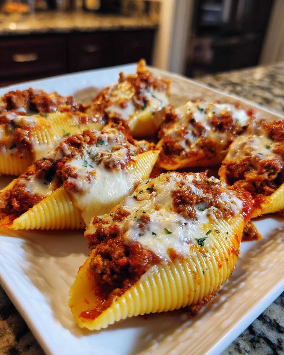 Close-up of baked stuffed shells filled with meat sauce and topped with melted mozzarella cheese.