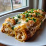 Close-up of cheesy shrimp enchiladas filled with rice and shrimp, garnished with fresh cilantro.