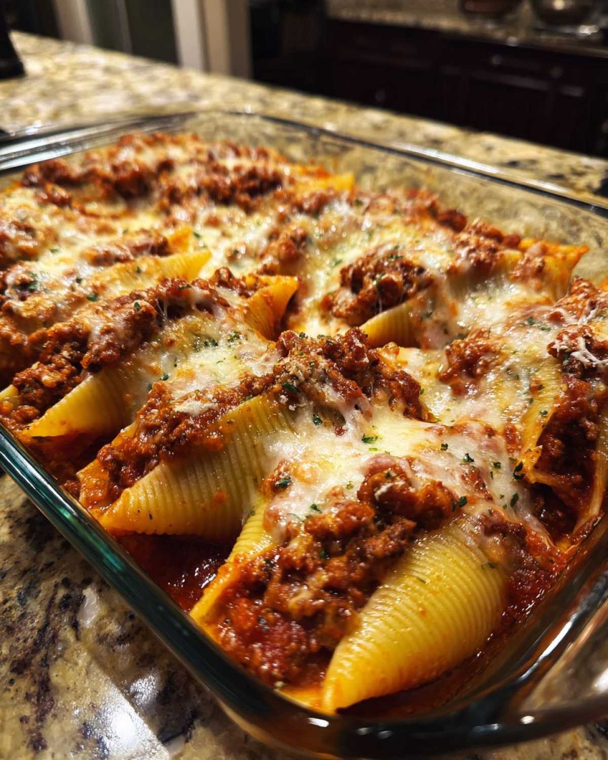 Close-up of baked stuffed shells covered in meat sauce and melted mozzarella cheese, ready to serve.