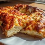 Two thick slices of white pizza with a bubbly, browned cheese topping resting on a white plate.