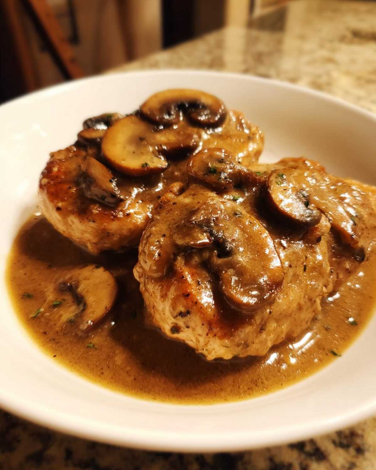 Two golden-brown chicken cutlets smothered in rich brown mushroom sauce, classic chicken marsala.