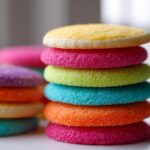 Stack of colorful sugar cookies topped with sugar crystals, demonstrating sugar cookie icing that hardens.