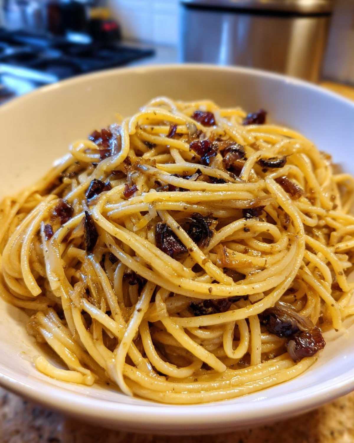 Close-up of creamy caramelized onion pasta, featuring spaghetti coated in a rich sauce with dark, sweet caramelized onions.
